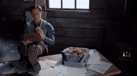 a man is sitting at a desk with his feet up and a box of pretzels on the table .