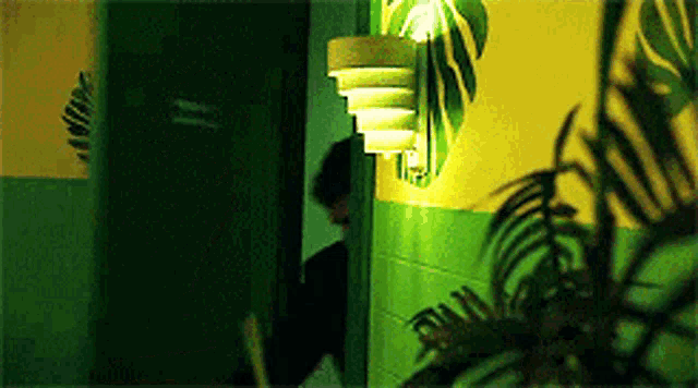 a person is standing in a dark room with a green wall