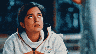 a woman wearing a white and orange jacket with the word champions on it