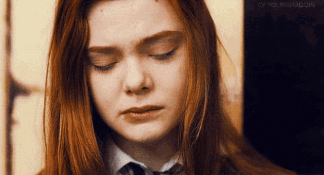 a woman with red hair is crying with her eyes closed and wearing a tie .