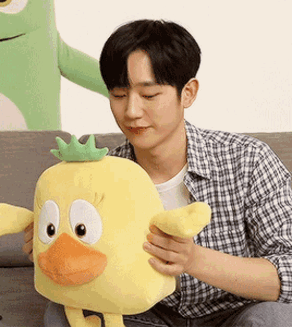 a man sitting on a couch holding a stuffed duck