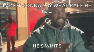 a man in a green jacket is standing in front of a car and talking about race .