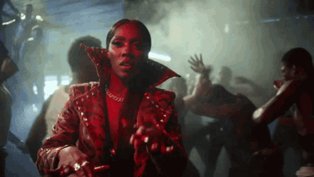 a woman in a red jacket is dancing in front of a crowd of people
