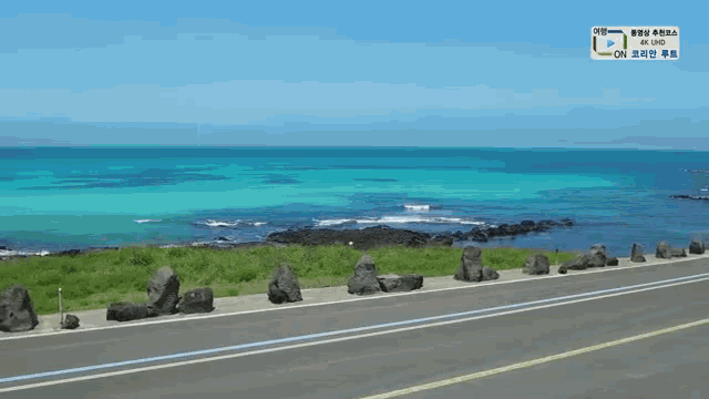 a road going towards the ocean with a sign that says 4k uhd on it