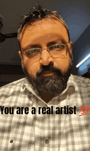a man with glasses and a beard has the words " you are a real artist " written on his shirt