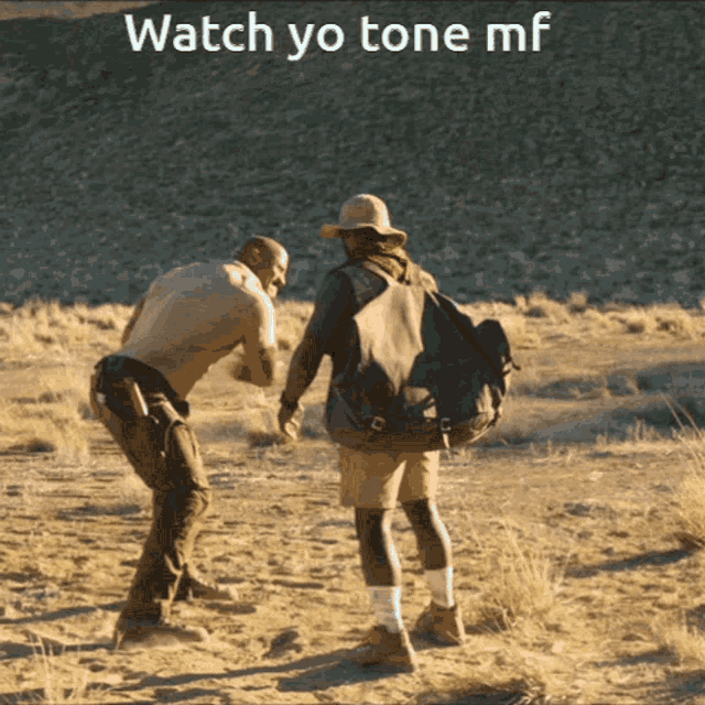 two men standing in the dirt with the words watch yo tone mf behind them