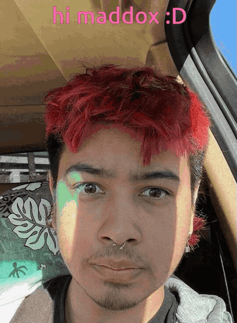 a man with red hair is sitting in a car with the words hi maddox : d above him