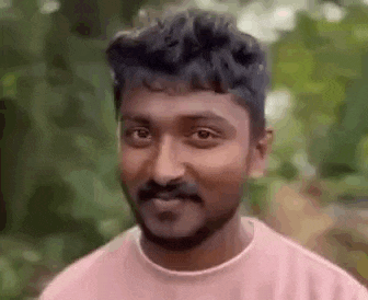 a man with a beard is wearing a pink shirt and making a funny face .