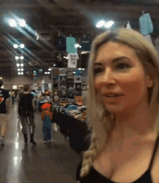 a woman in a black tank top is standing in a store with a t-shirt that says ' a ' on it