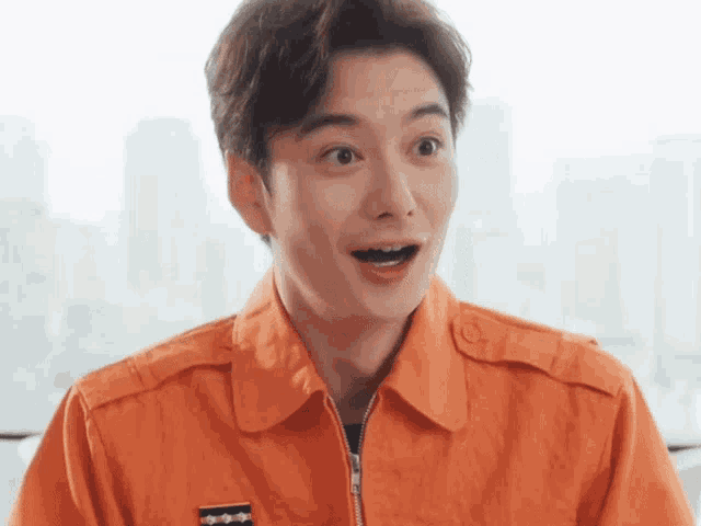 a man in an orange jacket is making a funny face .