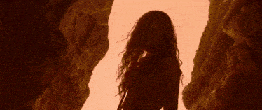 a naked woman with long red hair is standing in a canyon