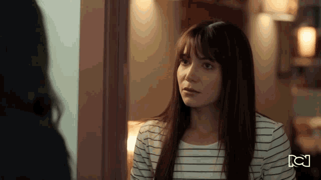 a woman in a striped shirt is talking to another woman in a room .