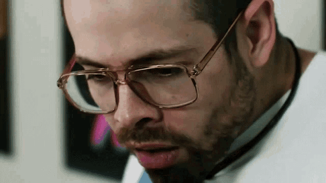 a man wearing glasses and a stethoscope looks down
