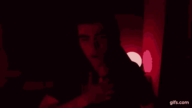 a man is talking on a cell phone in a dark room .