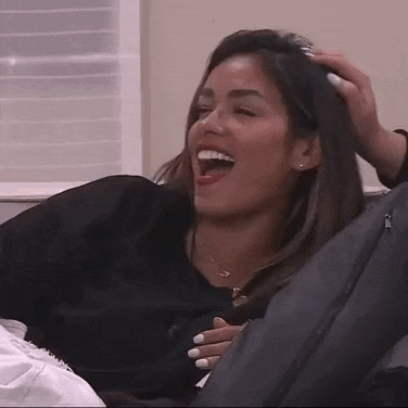 a woman is laying on a couch laughing and holding her chest .