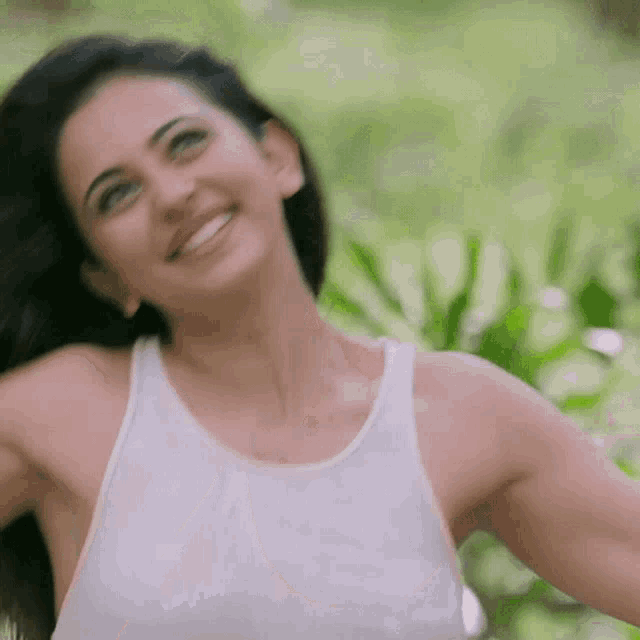 a woman in a white tank top is smiling