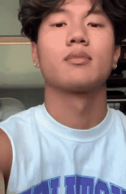 a young man wearing a white tank top with a purple letter t