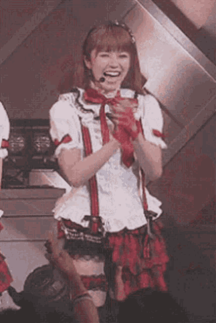 a woman in a red and white dress is smiling and holding a microphone in her hand .