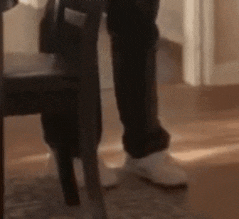 a person is standing next to a chair in a room with their legs crossed .