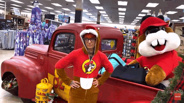 a woman in a beaver costume stands in front of a red truck with a propane tank in the back