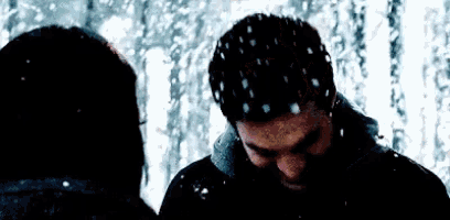 a man and a woman are standing in the snow with snow falling on them .