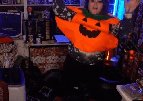 a woman wearing an orange pumpkin sweater is dancing in front of a top fundraiser sign