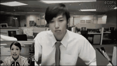 a man in a white shirt and tie is sitting in front of a woman in an office cubicle .