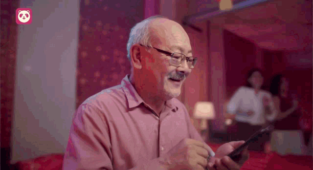 an older man with glasses and a mustache is smiling while looking at his phone