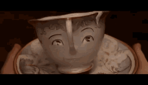 a person is holding a cup of tea with a face drawn on it .