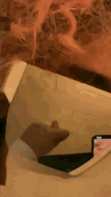 a person is holding a cell phone in their hand while sitting on a couch .