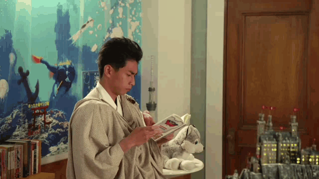 a man in a kimono is reading a magazine in front of a wall with a picture of a scuba diver on it