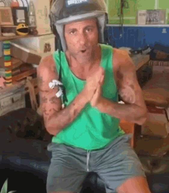 a man in a green tank top and shorts is wearing a helmet with the word bell on it