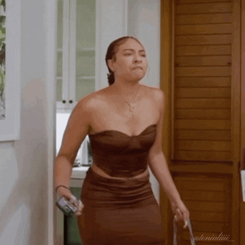 a woman in a strapless top and skirt is standing in a doorway