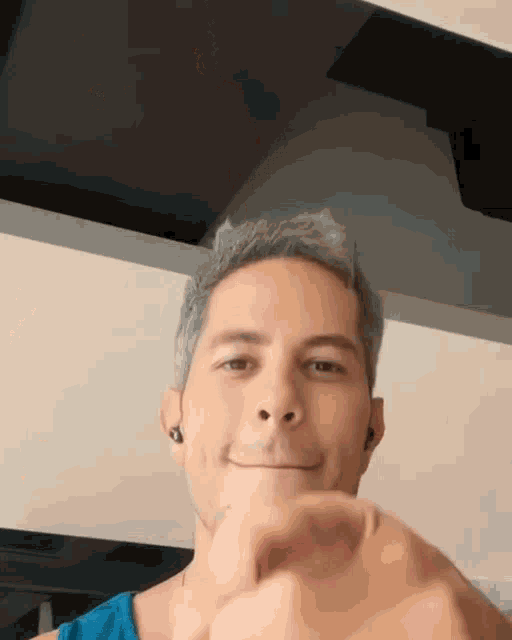 a man wearing ear buds is smiling and making a heart shape with his hand .
