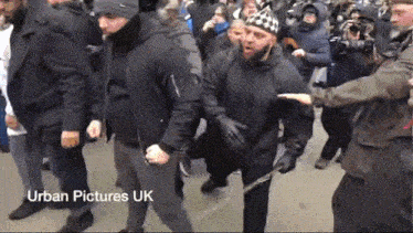 a group of people are walking down a street and the words urban pictures uk are on the bottom right