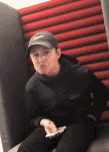 a boy wearing a black nike hat is sitting on a couch