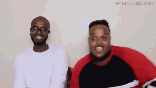 two men are sitting next to each other and smiling .