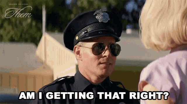 a police officer is talking to a little girl while wearing sunglasses .