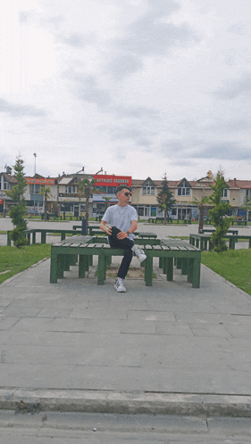 a man sits on a bench in front of a red sign that says ' istanbul ' on it