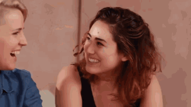 two women are sitting next to each other and smiling .