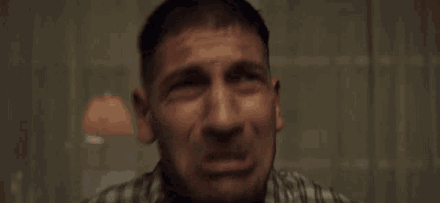 a man in a plaid shirt is screaming with his mouth wide open .