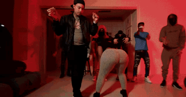 a group of people are dancing in a room with red lights behind them