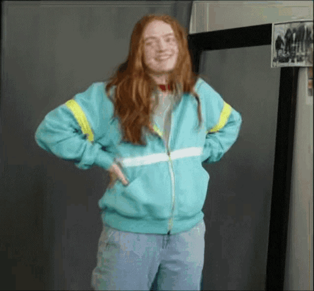 a woman with red hair is wearing a blue jacket