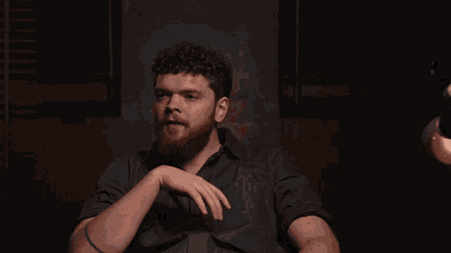 a man with a beard and a tattoo on his arm reaches out