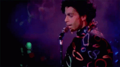 a man in a colorful shirt is singing into a microphone on stage .