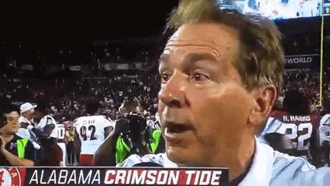a man stands in front of an alabama crimson tide sign