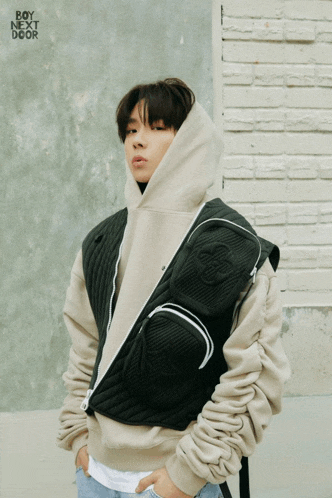 a young man wearing a hoodie and a vest with the words boy next door on the bottom