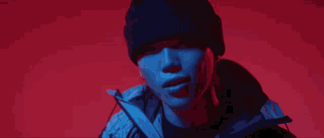a close up of a woman wearing a beanie and a jacket against a red background .