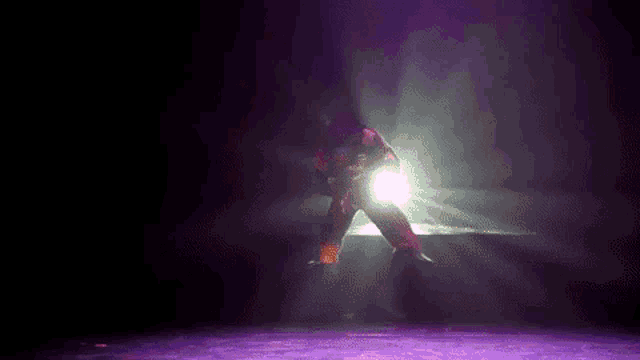 a person is dancing on a stage with purple lights