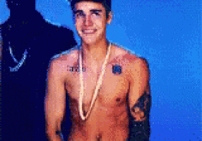 a shirtless man wearing a pearl necklace and a tattoo on his chest